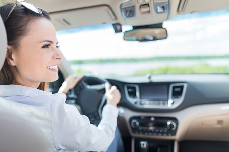Beautiful young woman sitting in the interior of a new car with a smile. He is glad he is a driver.の写真素材