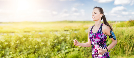 Beautiful, young woman running on the water's edge by the country road. Jogging concept.の写真素材