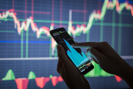 Businessman checking stock market data. He using a mobile phone. Analysis economy data on forex earn graph. の写真素材