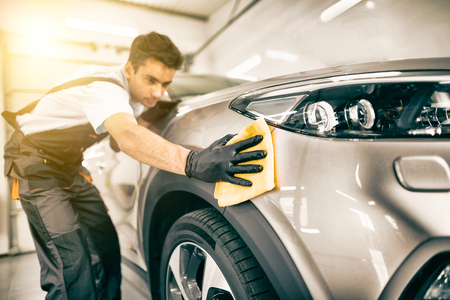 Car detailing - the man holds the microfiber in hand and polishes the car. Selective focus.の写真素材