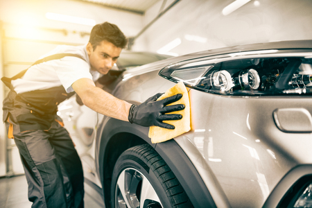 Car detailing - the man holds the microfiber in hand and polishes the car. Selective focus.