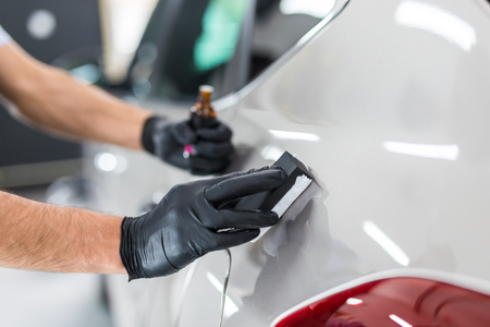 Car detailing - Man applies nano protective coating to the car. Selective focus.