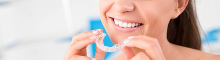 Woman wearing orthodontic silicone trainer. Invisible braces aligner. Mobile orthodontic appliance...
