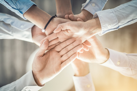 Close up top view of young business people putting their hands together. Stack of hands. Unity and teamwork concept.の写真素材
