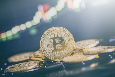 Bitcoin gold coin and defocused chart background. Virtual cryptocurrency concept.の写真素材