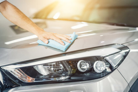 Car detailing - the man holds the microfiber in hand and polishes the car. Selective focus.の写真素材