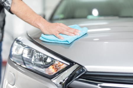 Car detailing - the man holds the microfiber in hand and polishes the car. Selective focus.の写真素材