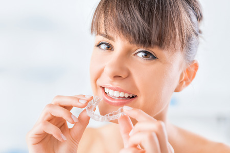 Woman wearing orthodontic silicone trainer. Invisible braces aligner. Mobile orthodontic appliance for dental correction.の写真素材