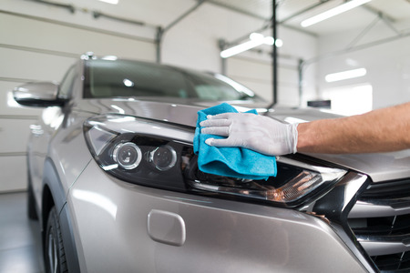 Car detailing - the man holds the microfiber in hand and polishes the car. Selective focus.の写真素材