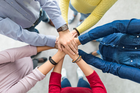 Close up top view of young business people putting their hands together. Stack of hands. Unity and teamwork concept.