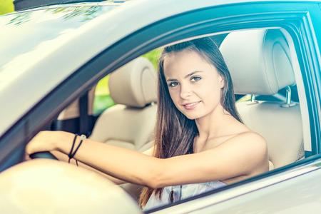 Beautiful young woman sitting in the interior of a new car with a smile. He is glad he is a driver.の写真素材
