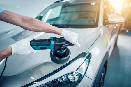 Car detailing - Man holds a polisher in the hand and polishes the car. Selective focus.の写真素材