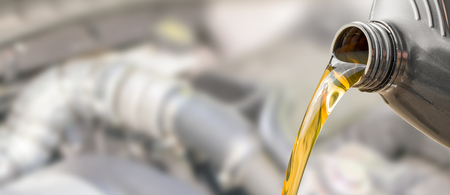 Pouring oil to car engine. Fresh oil poured during an oil change to a car.の写真素材