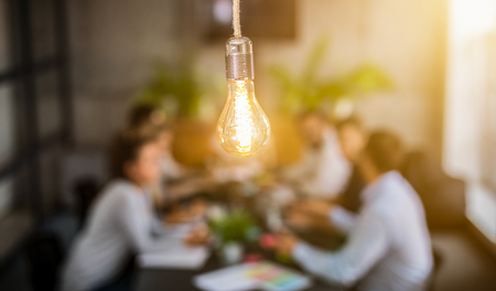 Young business people are discussing together a new startup project. A glowing light bulb as a new idea.の写真素材