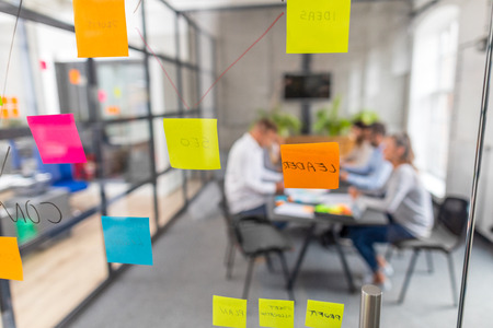 Business people meeting at office and use post it notes to share idea. Brainstorming concept. Sticky note on glass wall.の写真素材