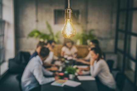 Young business people are discussing together a new startup project. A glowing light bulb as a new idea.の写真素材
