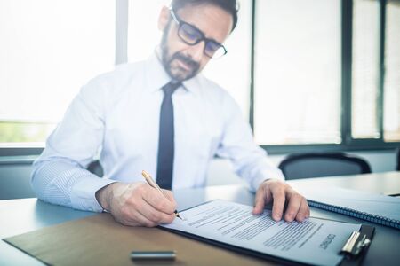Business man signing contract document on office desk, making a deal.の写真素材