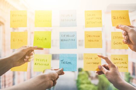 Business people meeting at office and use post it notes to share idea. Brainstorming concept. Sticky note on glass wall.の写真素材