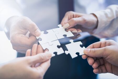 A group of business people assembling jigsaw puzzle. The concept of cooperation, teamwork, help and support in business.の写真素材