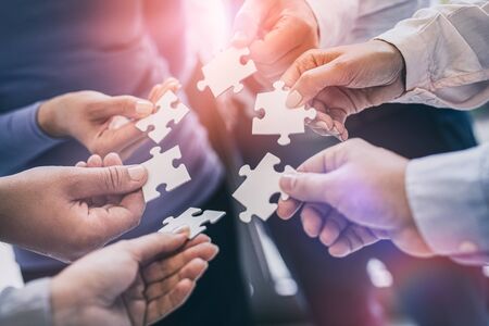 A group of business people assembling jigsaw puzzle. The concept of cooperation, teamwork, help and support in business.の写真素材