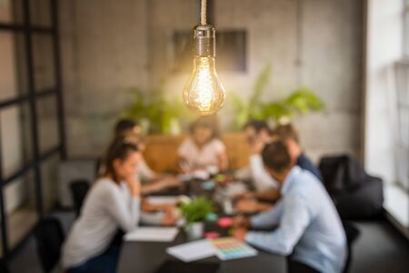 Young business people are discussing together a new startup project. A glowing light bulb as a new idea.の写真素材