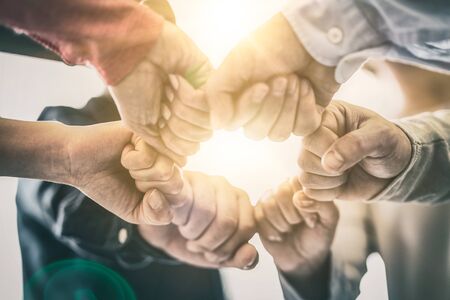Dramatic moment. A group people hold strong hands. Sign of trust and teamwork. Corporate meeting concept.の写真素材