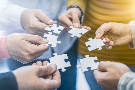 A group of business people assembling jigsaw puzzle. The concept of cooperation, teamwork, help and support in business.の写真素材