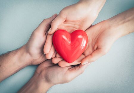 An adult, mother and child hold a red heart in their hands. Concept for charity, health insurance, love, international cardiology day.の写真素材