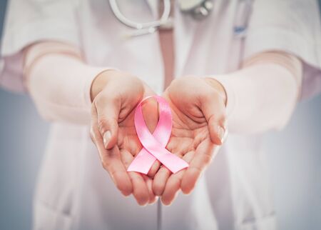 Pink ribbon in hands a doctor. National cancer survivor day.の写真素材