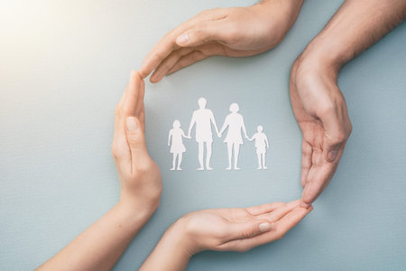 Hands with cut out paper silhouette on table. Family care concept.の写真素材