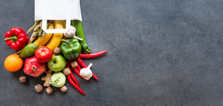 Healthy food selection: fruits, vegetable, seeds, superfood, leaf vegetable on gray concrete...