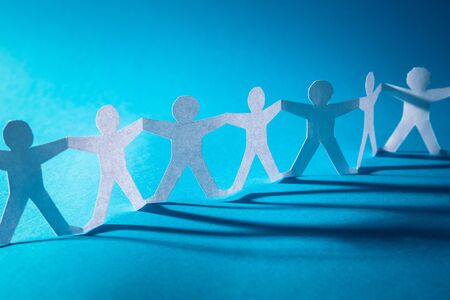 Team of paper chain people. Human chain with light and shadow. Blue tone background.の写真素材