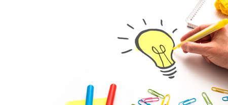 Creative new idea. Innovation, brainstorming, inspiration and solution concepts. Designer drawing a light bulb.の写真素材