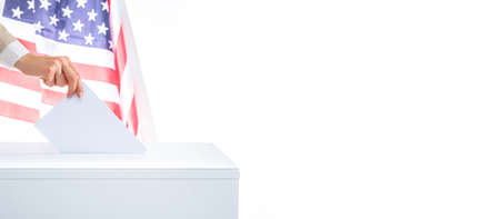 The voter holds his vote ballot paper and places it in the ballot box. Filling in ballots and casting votes in booths at polling station. The concept of free democratic vote elections.の写真素材