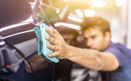 Car detailing - the man holds the microfiber in hand and polishes the car. Selective focus.の写真素材