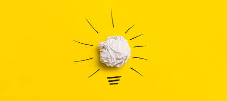 Creative new idea. Innovation, brainstorming, inspiration and solution concepts. Light bulb with crumpled paper on yellow background.の写真素材