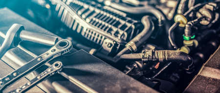 Auto mechanic working and repair on car engine in mechanics garage. Car service. Man with wrench at workshop.の写真素材