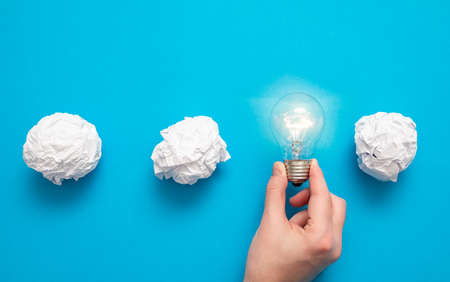 Creative new idea. Innovation, brainstorming, inspiration and solution concepts. Light bulb and crumpled paper on blue background.の写真素材