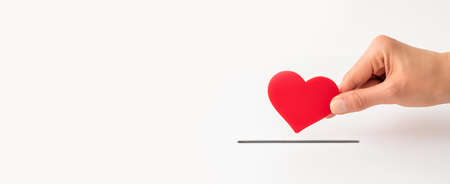 The concept of charity, love, donate and helping hand. Woman's hand places heart in the donation slot. Donor of blood or human organs, saving lives.の写真素材