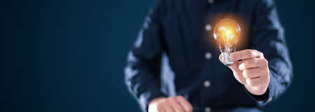 Creative new idea. Innovation, brainstorming, inspiration and solution concepts. The man is holding light bulb. Copy space background.の写真素材