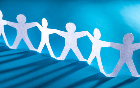 Team of paper chain people. Human chain with light and shadow. Blue tone background.の写真素材