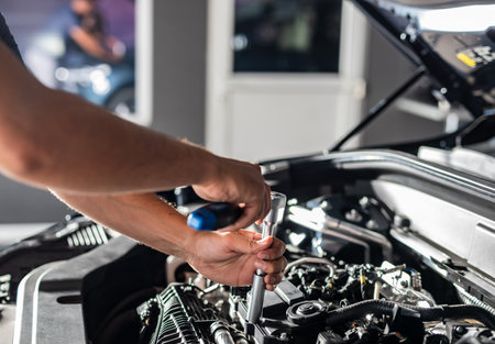 Auto mechanic working and repair on car engine in mechanics garage. Car service. Man with wrench at workshop.の写真素材