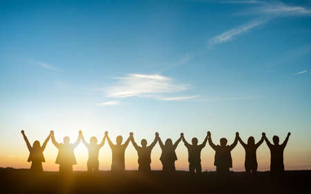 Silhouette of group happy business team making high hands over head in sunset sky background for business teamwork concept.の写真素材