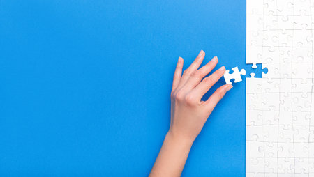 Hand put the last piece of jigsaw puzzle. Complete the mission. Business concept.の写真素材