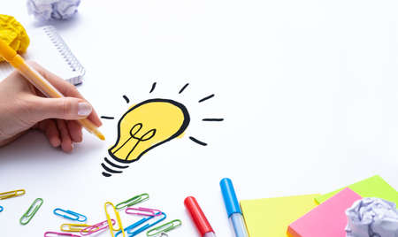Creative new idea. Innovation, brainstorming, inspiration and solution concepts. Designer drawing a light bulb.の写真素材