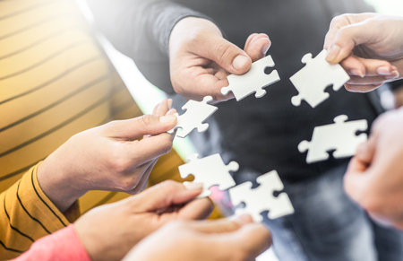 A group of business people assembling jigsaw puzzle. The concept of cooperation, teamwork, help and support in business.の写真素材