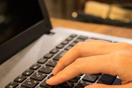 Hand of Asian woman student working on a laptop at a coffee shop