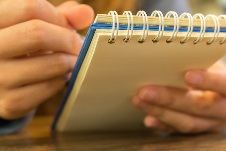 female hands with pen writing on notebook at coffee shopの写真素材