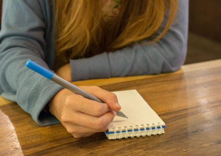 female hands with pen writing on notebook at coffee shopの写真素材