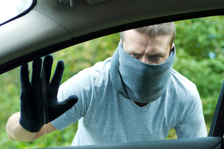 Thief wearing black clothes and leather coat stealing a car